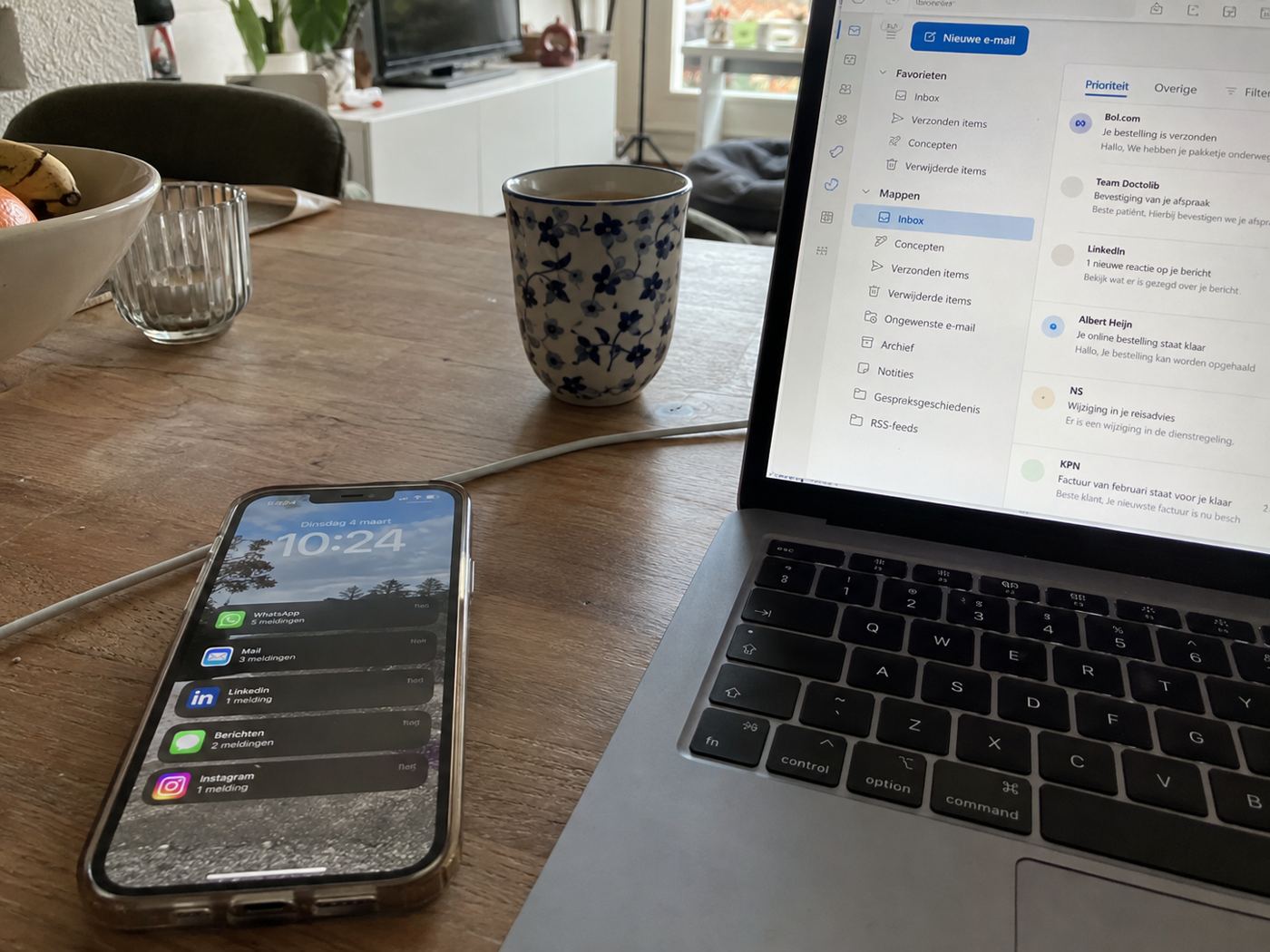 Een telefoon vol meldingen naast een laptop